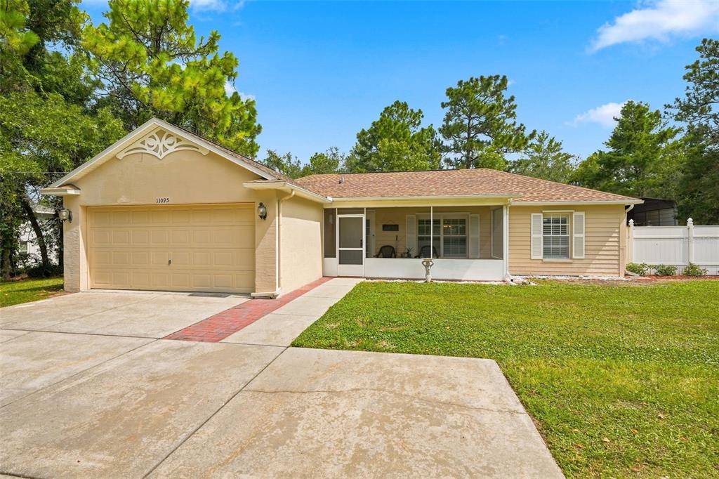 A single-story house with a beige stucco facade, a two-car garage, and a screened porch — 11095 FLATWOOD AVENUE, WEEKI WACHEE, FL