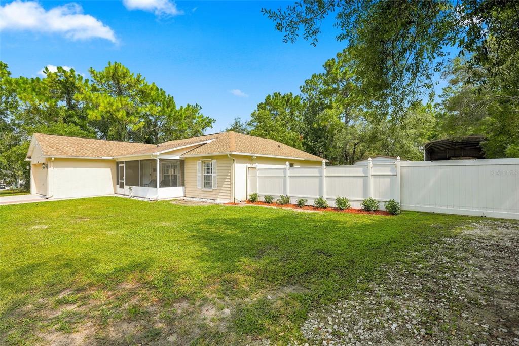 A yellow house with a screened-in porch and a white vinyl fence in the backyard — 11095 FLATWOOD AVENUE, WEEKI WACHEE, FL