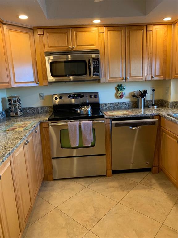 A kitchen features light wood cabinets, granite countertops, and stainless steel appliances — 1001 BENJAMIN FRANKLIN DRIVE UNIT 508, SARASOTA, FL