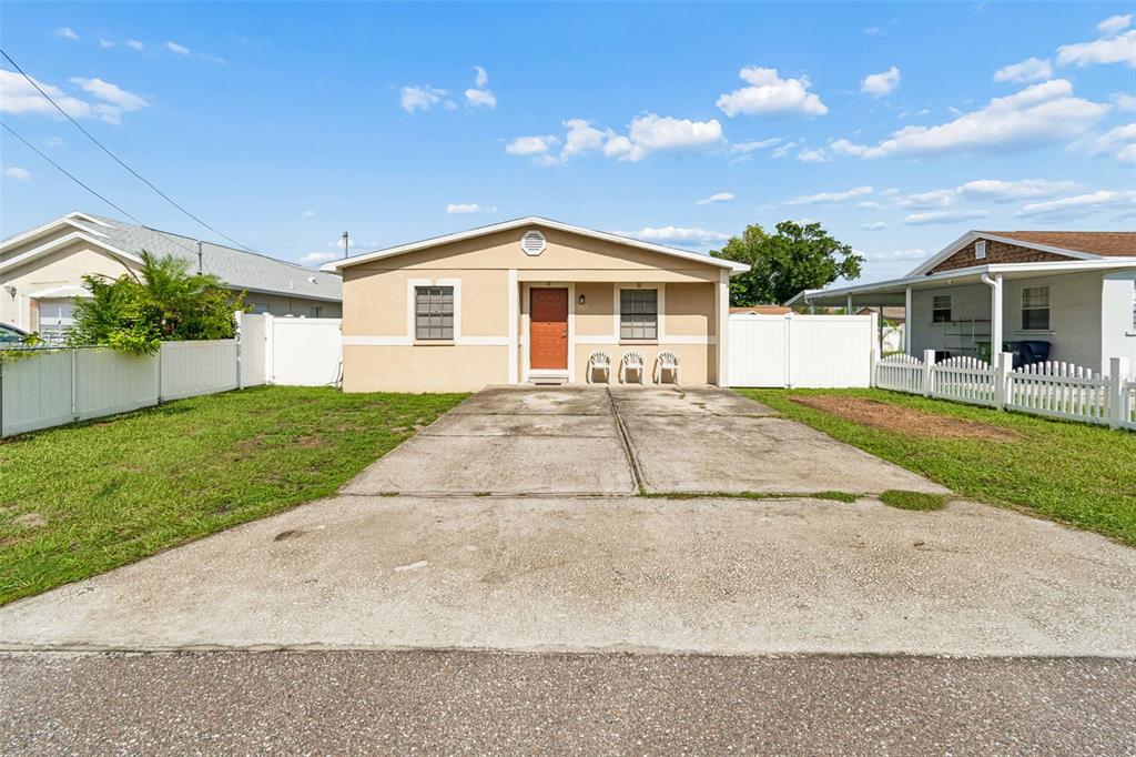 A single-story house with a tan exterior, a concrete driveway, and white vinyl fencing — 5120 N MATANZAS AVENUE, TAMPA, FL