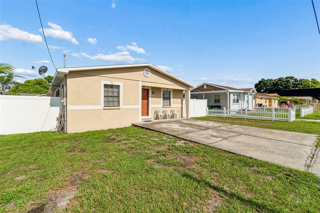 A tan single-story house with a concrete driveway and a white vinyl fence — 5120 N MATANZAS AVENUE, TAMPA, FL