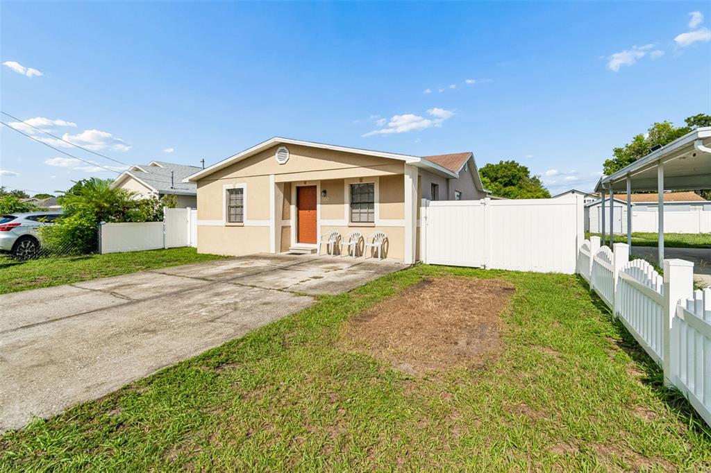 A single-story tan house with a concrete driveway and a white vinyl fence — 5120 N MATANZAS AVENUE, TAMPA, FL
