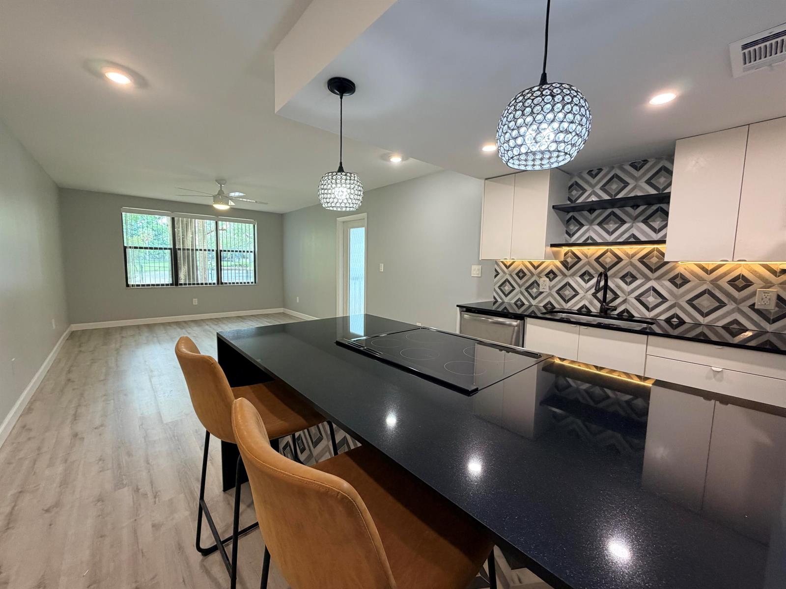 A modern kitchen features a black island, white cabinets, and a geometric patterned backsplash — 4501 W Mcnab Road # 11, Pompano Beach FL 33069, POMPANO BEACH, FL