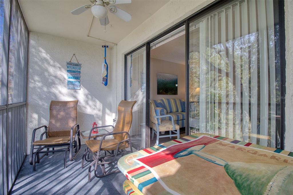 A screened-in balcony features two wicker chairs, a small table, and a ceiling fan — 3134 LAKE PINE WAY UNIT G2, TARPON SPRINGS, FL