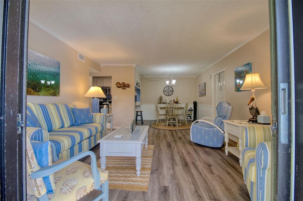 A living and dining area with striped furniture, wood-look flooring, and a white coffee table — 3134 LAKE PINE WAY UNIT G2, TARPON SPRINGS, FL