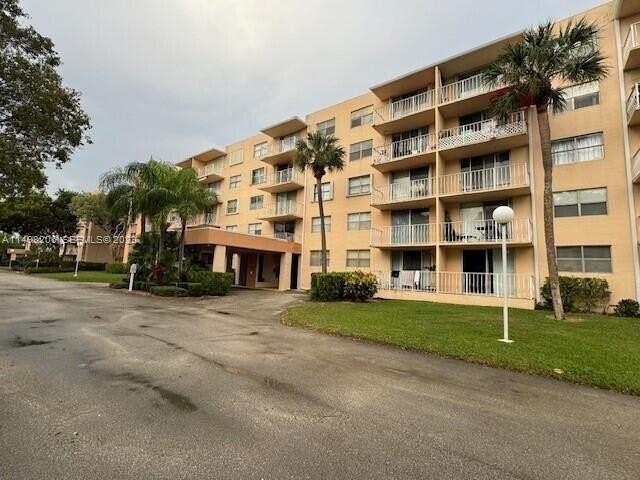 A multi-story apartment building with balconies and palm trees sits beside a paved driveway — 480 Executive Center Dr # 4L, West Palm Beach FL 33401, WEST PALM BEACH, FL