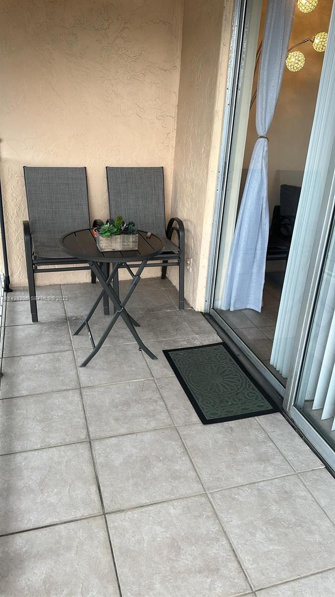 A small balcony features two gray chairs, a round metal table, and a door mat — 480 Executive Center Dr # 4L, West Palm Beach FL 33401, WEST PALM BEACH, FL