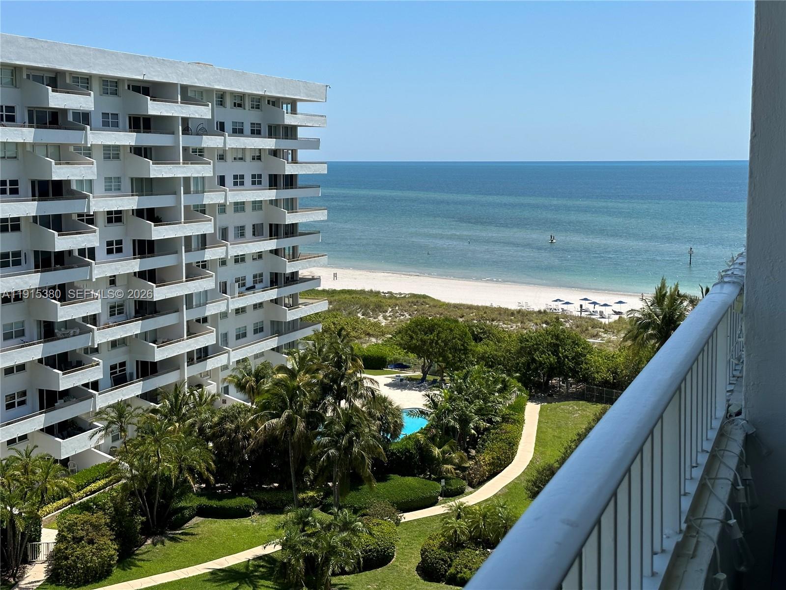 A high-angle view shows a beachside condominium building, swimming pool, and the ocean — 199 Ocean Lane Dr # 1004, Key Biscayne FL 33149, KEY BISCAYNE, FL