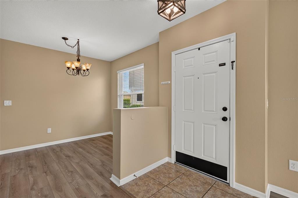An entryway with tile flooring leads to a dining area featuring wood-look floors and a chandelier — 817 ASHENTREE DRIVE, PLANT CITY, FL