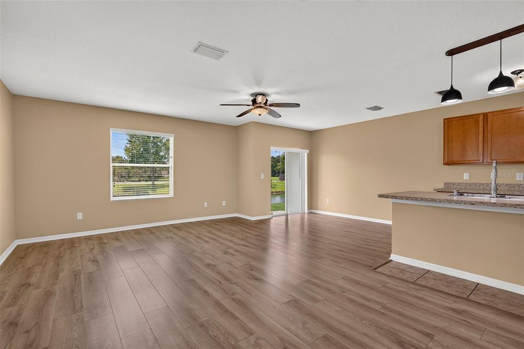An open-concept living area with wood-look flooring, a ceiling fan, and a kitchen breakfast bar — 817 ASHENTREE DRIVE, PLANT CITY, FL