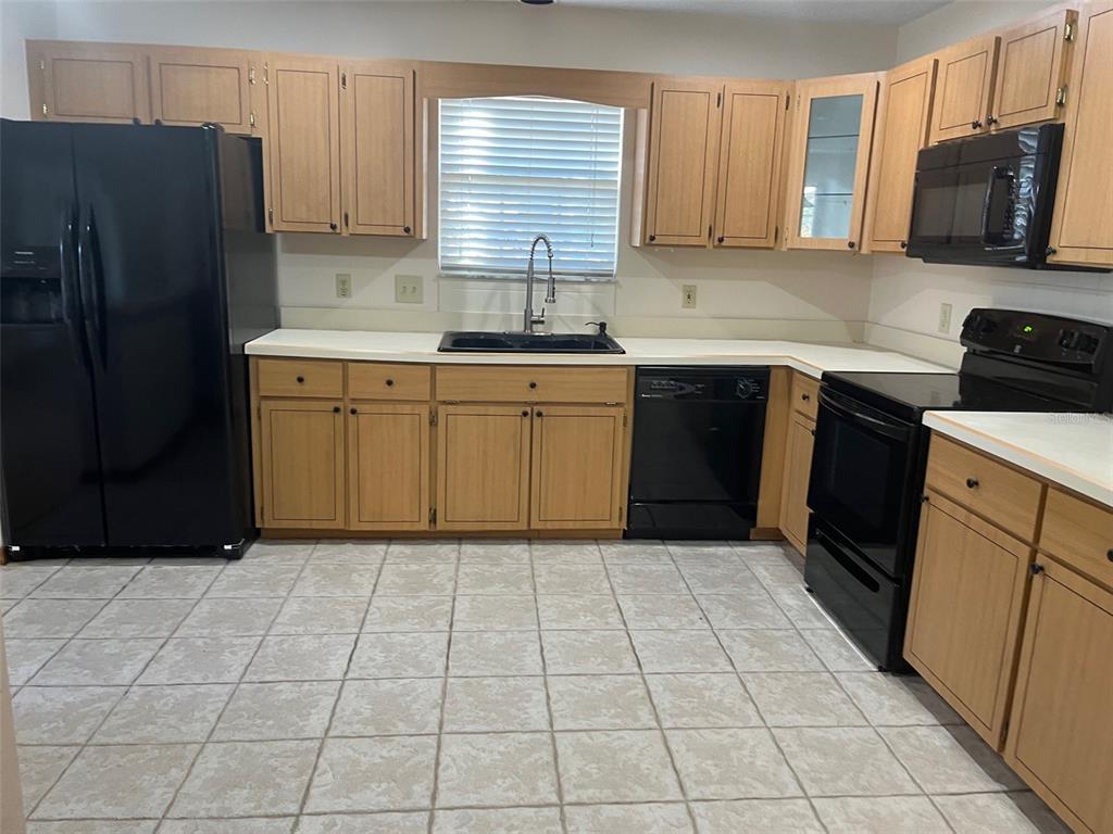 A kitchen features light wood cabinets, black appliances, white countertops, and tiled flooring — 175 CONRAD STREET, PORT ORANGE, FL