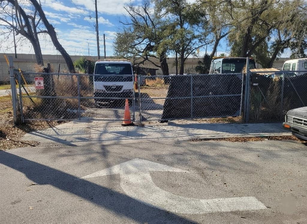 A chain-link fence with a gate encloses a gravel lot containing a white truck — 1200 29TH STREET, ORLANDO, FL