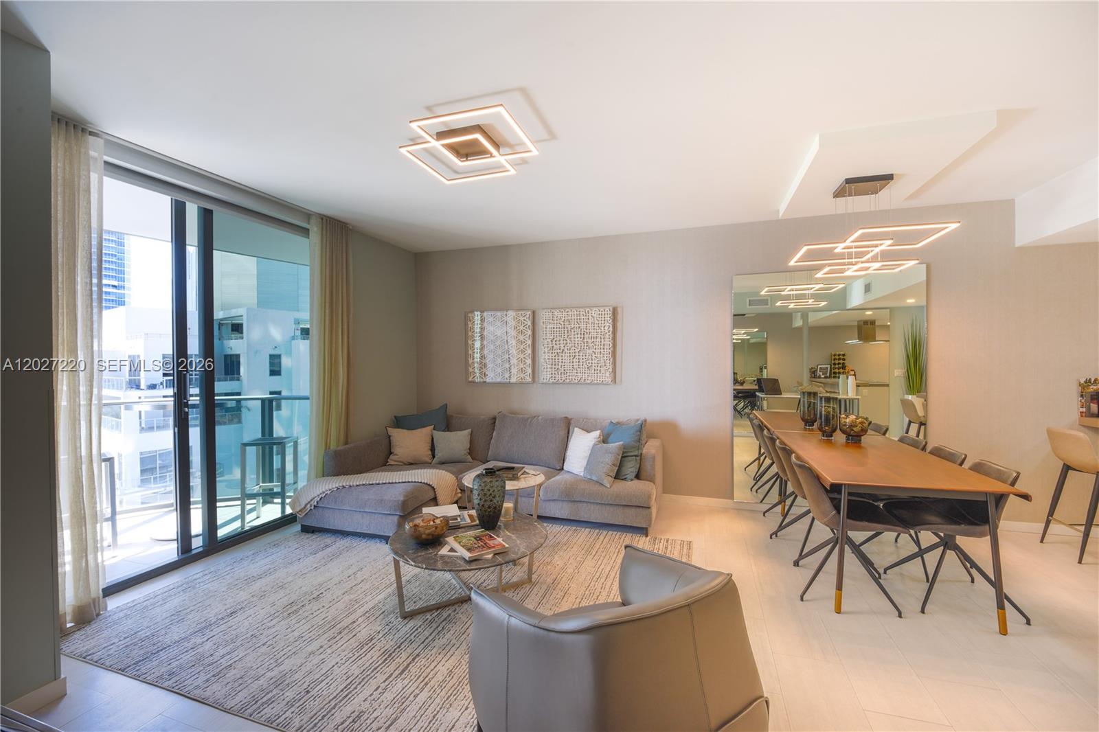 A modern living and dining area features a grey sectional sofa, dining table, and balcony — 1000 Brickell Plz # 3705, Miami FL 33131, MIAMI, FL