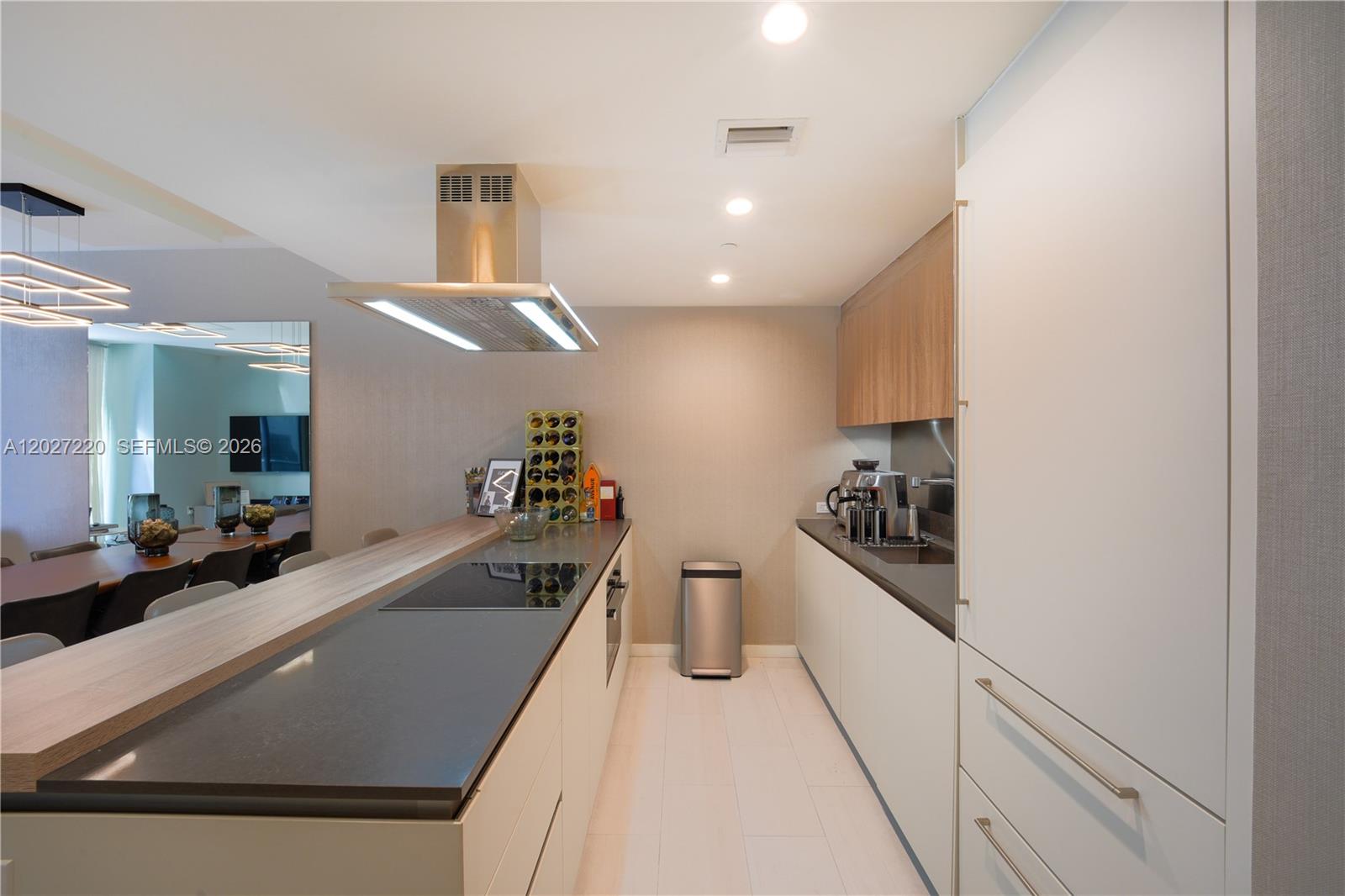 A modern kitchen features a central island with a cooktop, light cabinetry, and stainless appliances — 1000 Brickell Plz # 3705, Miami FL 33131, MIAMI, FL