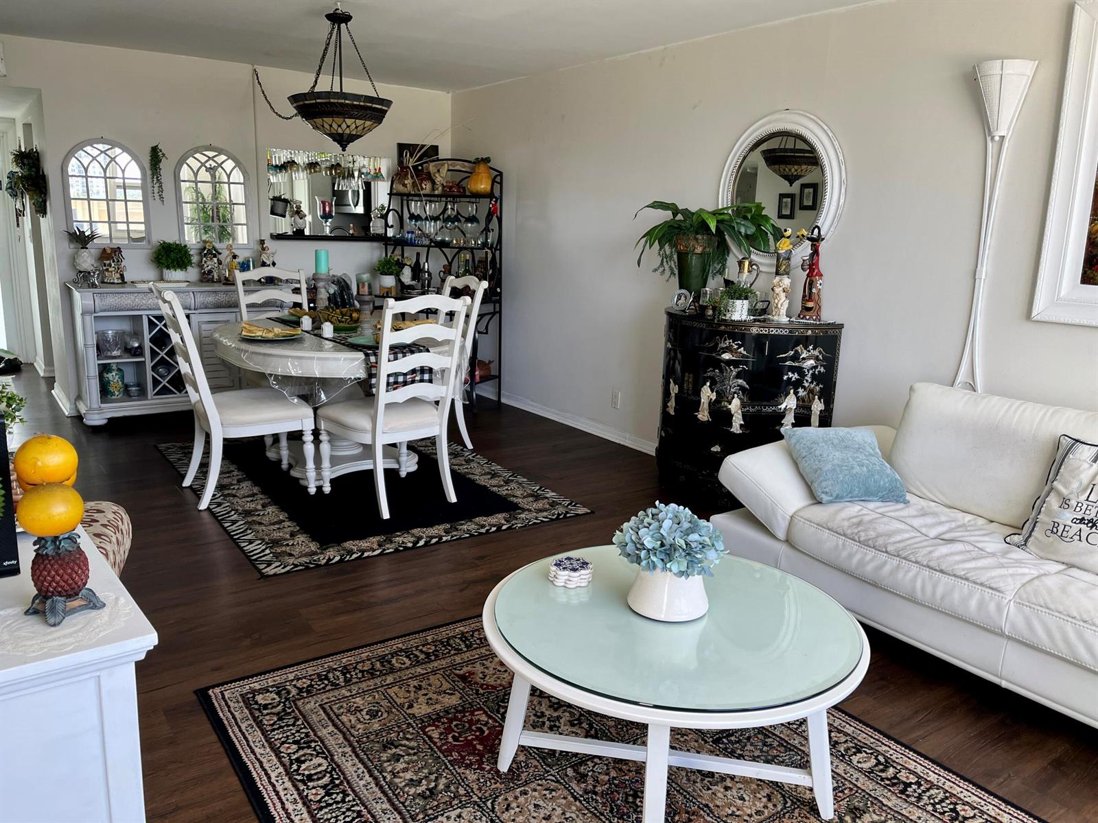 A living and dining room featuring white furniture, dark wood floors, and two area rugs — 201 N Ocean Boulevard # 302, Pompano Beach FL 33062, POMPANO BEACH, FL