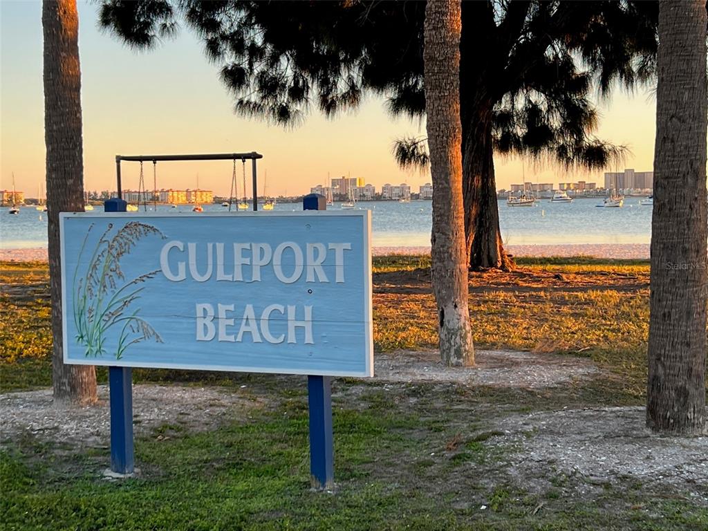 A sign for Gulfport Beach stands in a park with palm trees and water views — 2800 TIFTON ST UNIT 3, GULFPORT, FL