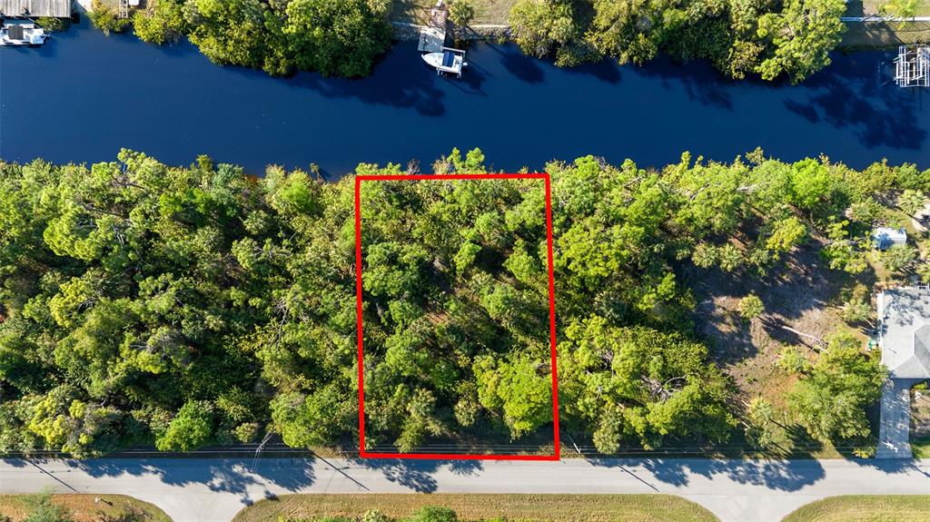 An aerial view shows a rectangular, wooded vacant lot bordering a canal — 425 CHESHIRE STREET, PORT CHARLOTTE, FL
