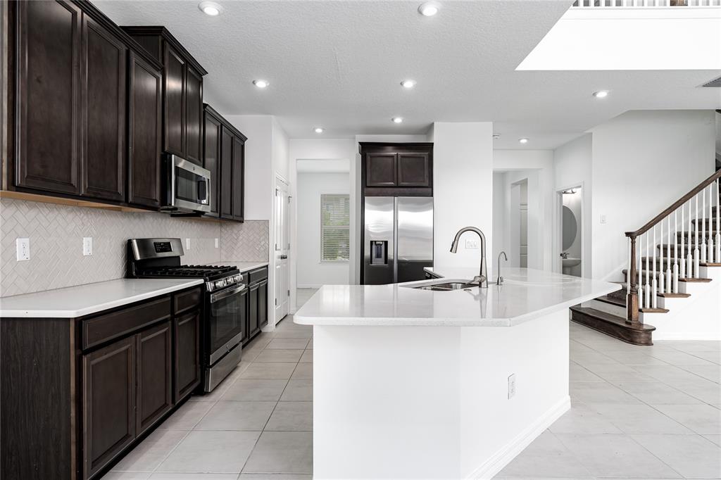 A kitchen features dark wood cabinets, white countertops, a center island, and tile flooring — 5719 MAIDENSTONE WAY, PALMETTO, FL