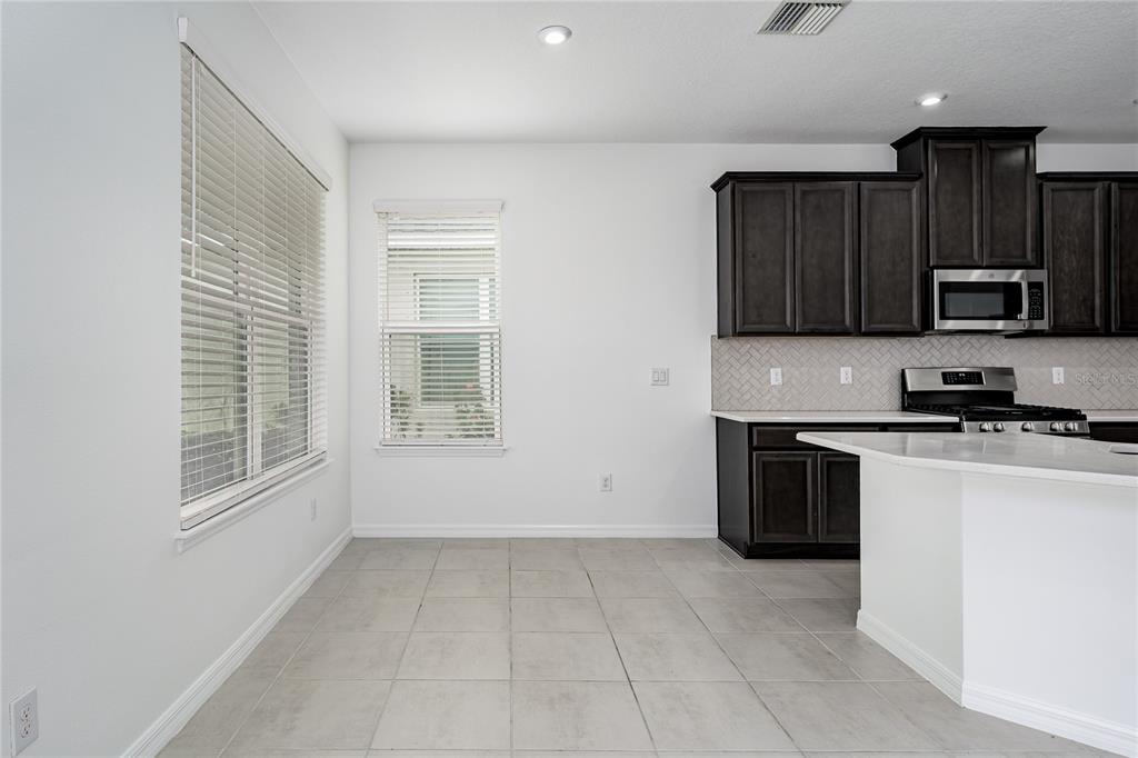A kitchen features dark wood cabinets, stainless steel appliances, and a tile floor — 5719 MAIDENSTONE WAY, PALMETTO, FL