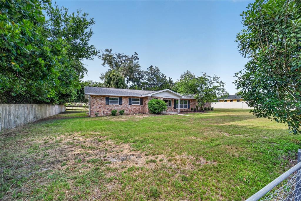A single-story brick house sits on a large, grassy lot with mature trees — 2421 NE 57TH PLACE, OCALA, FL