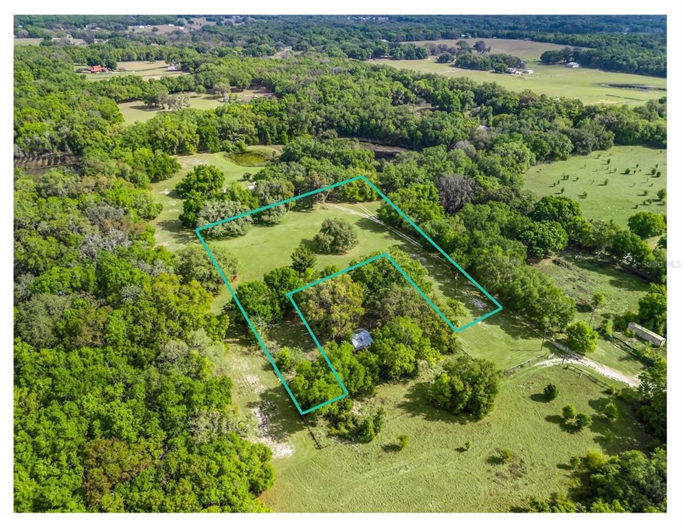 An aerial view shows a rural property with a house surrounded by trees and pasture — 747 COUNTY ROAD 466A, FRUITLAND PARK, FL
