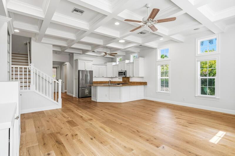 An open-concept kitchen and living area features a coffered ceiling, hardwood floors, and stairs — VERO BEACH, FL