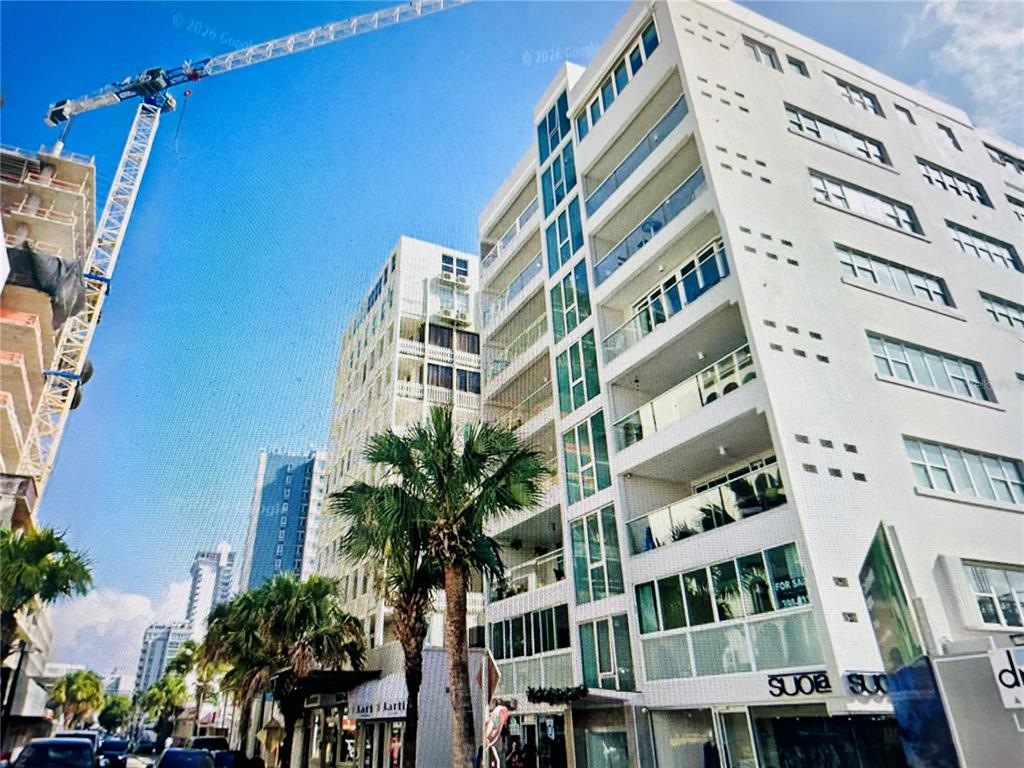 A low-angle exterior view of a modern white multi-story building with balconies and a crane — 1124 ASHFORD AVENUE UNIT 6A, SAN JUAN, PR