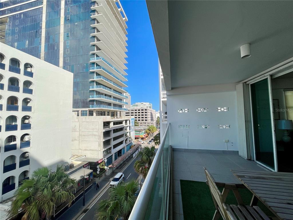 A balcony with a glass railing overlooks a city street and nearby high-rise buildings — 1124 ASHFORD AVENUE UNIT 6A, SAN JUAN, PR