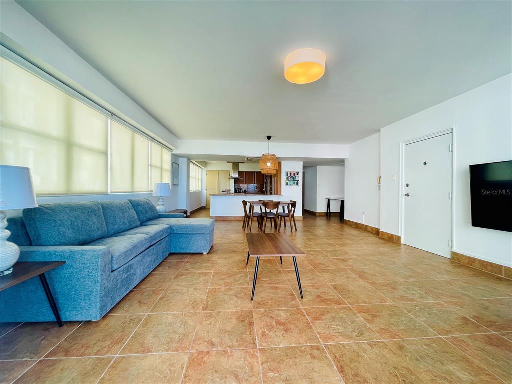 A living room with a blue sectional sofa, tile flooring, and an open kitchen area — 1124 ASHFORD AVENUE UNIT 6A, SAN JUAN, PR