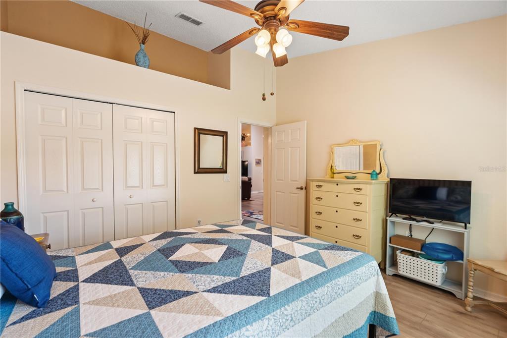 A bedroom features a quilt-covered bed, a dresser with a mirror, and a ceiling fan — 409 CANDLESTONE COURT, SPRING HILL, FL