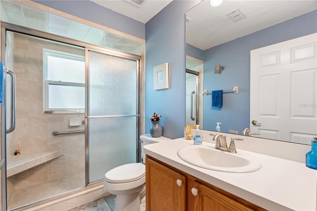 A bathroom features a walk-in shower with glass doors, a vanity, and a toilet — 409 CANDLESTONE COURT, SPRING HILL, FL