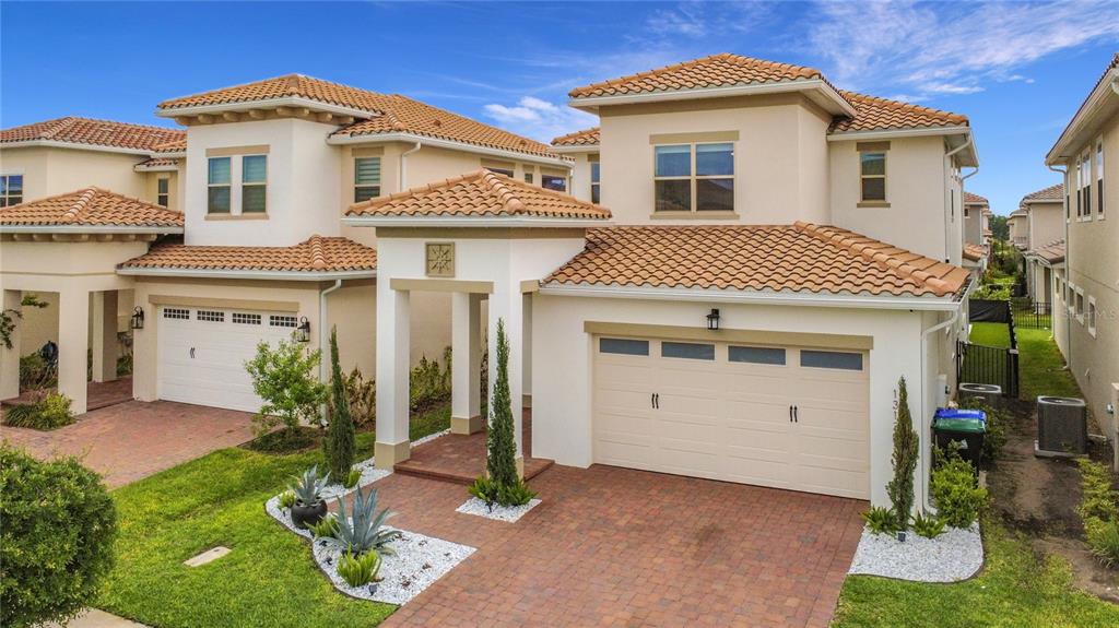 A two-story house with a tiled roof, two garages, and a brick-paved driveway — 13130 WEAVER AVENUE, ORLANDO, FL