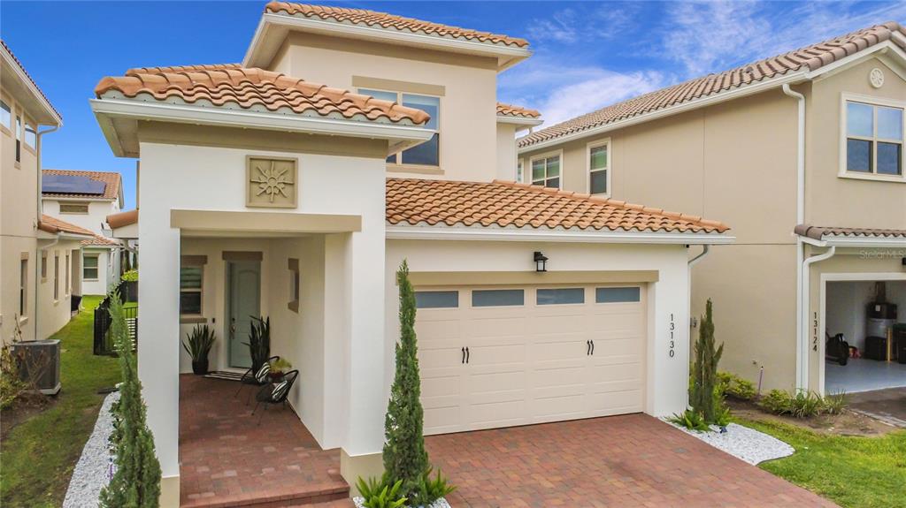 A two-story suburban house with a tiled roof, a garage, and a covered front porch — 13130 WEAVER AVENUE, ORLANDO, FL