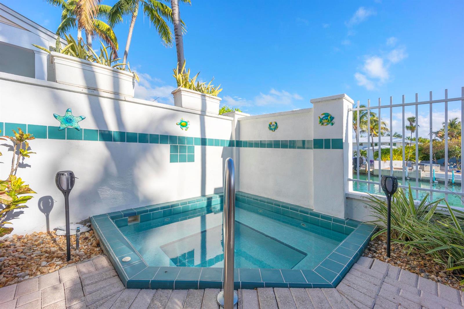 A tiled outdoor hot tub sits on a brick patio against a white privacy wall — 7031 Harbor Village Drive # 7031, FL 33050, FL