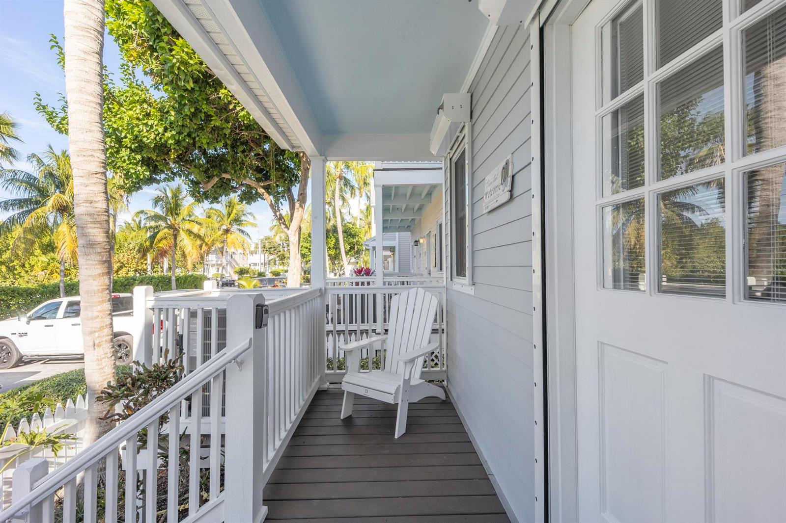 A white Adirondack chair sits on a covered wooden porch with light blue ceiling panels — 7031 Harbor Village Drive # 7031, FL 33050, FL