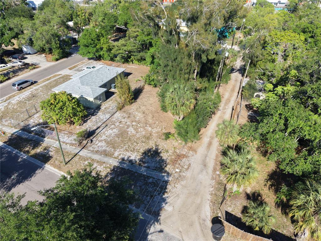 An aerial view shows a single-story house next to a vacant lot and a dirt road — 14TH AVENUE S, ST PETERSBURG, FL
