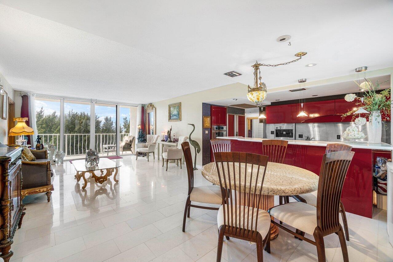 A bright living and dining area features white tile floors, red cabinets, and balcony views — 2774 S Ocean Boulevard # 708, Palm Beach FL 33480, PALM BEACH, FL