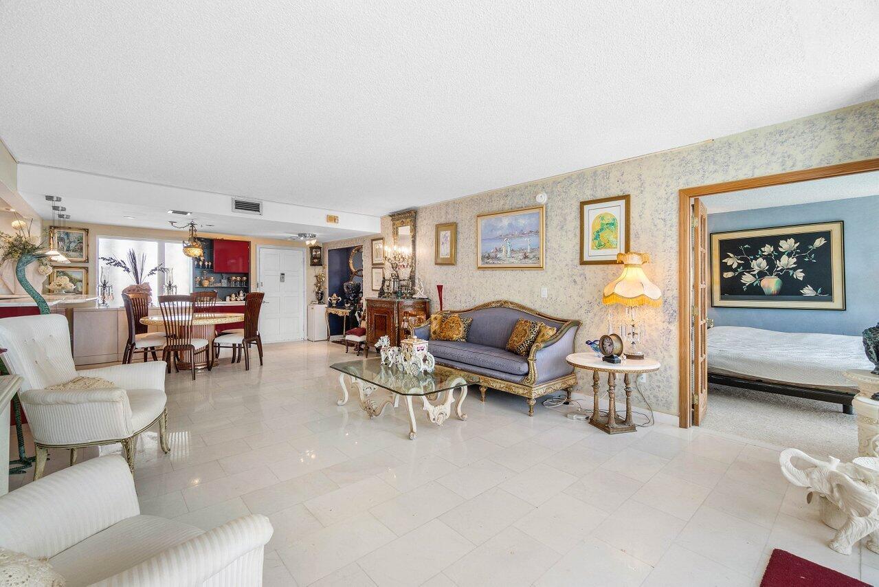 A living room with marble floors, a blue sofa, and an adjacent dining area — 2774 S Ocean Boulevard # 708, Palm Beach FL 33480, PALM BEACH, FL