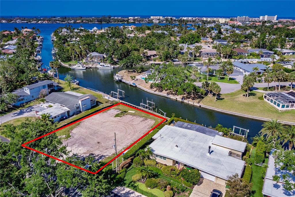 An aerial view shows a vacant, rectangular waterfront lot outlined in red next to houses — 1849 BAYWOOD DRIVE, SARASOTA, FL