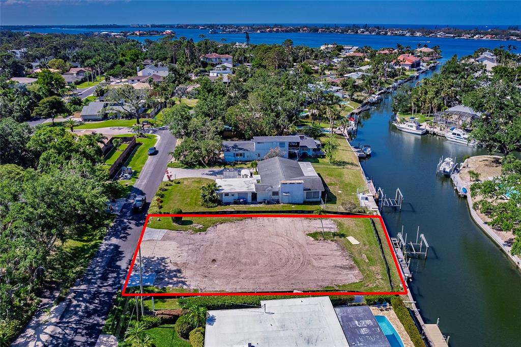 An aerial view shows a vacant, rectangular waterfront lot outlined in red next to a canal — 1849 BAYWOOD DRIVE, SARASOTA, FL