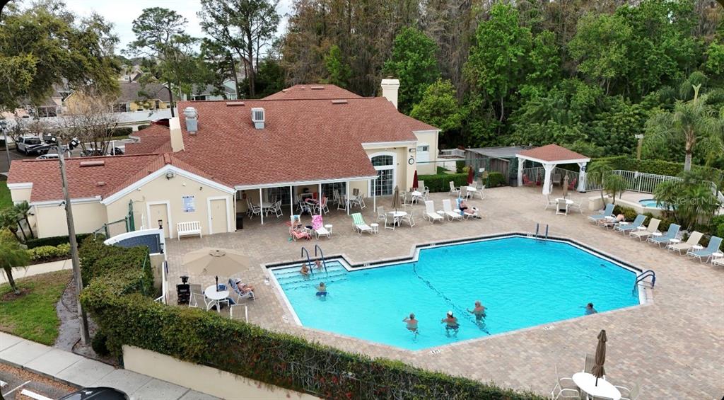 An aerial view of a community swimming pool and clubhouse with a red shingled roof — 7830 BECKET ST, NEW PORT RICHEY, FL