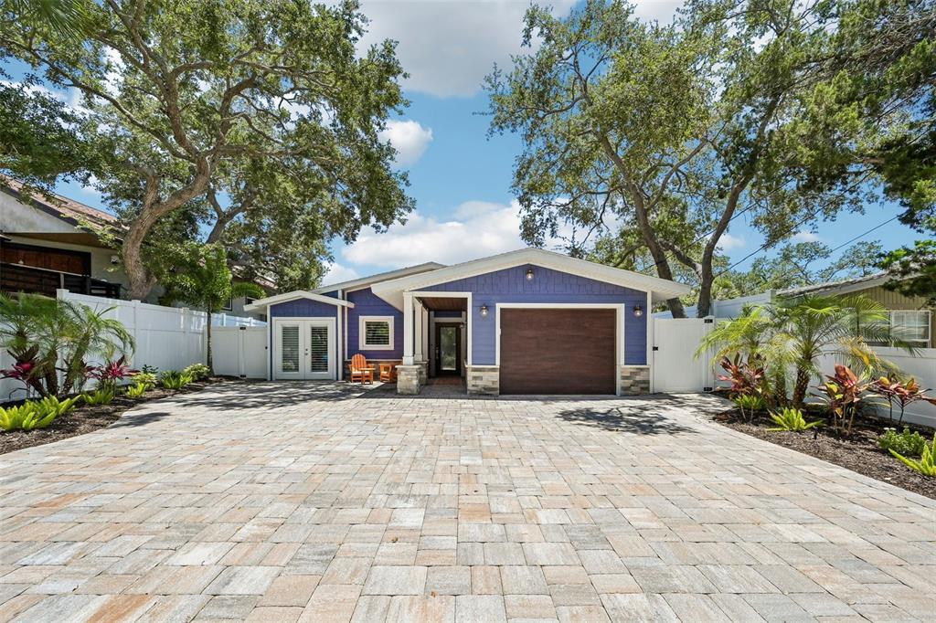 A blue house with a wooden garage door and a large paved driveway — 810 PLYMOUTH STREET, SARASOTA, FL