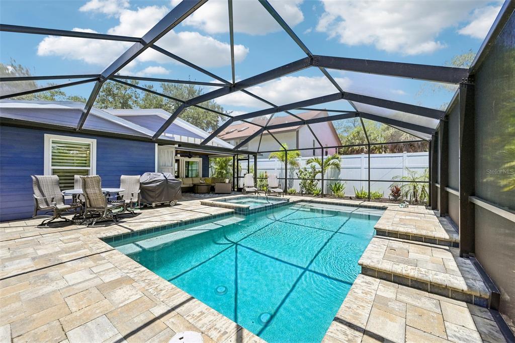 A screened-in patio features a swimming pool, a hot tub, and stone paver decking — 810 PLYMOUTH STREET, SARASOTA, FL