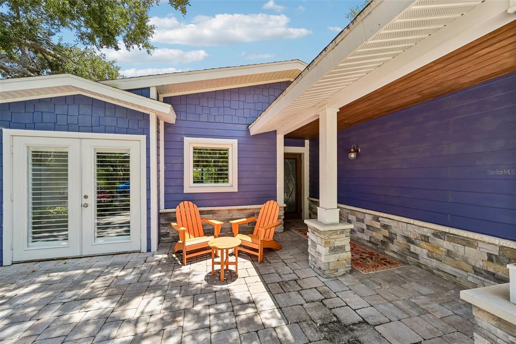 A purple house exterior features a stone-paved patio with two orange chairs and a table — 810 PLYMOUTH STREET, SARASOTA, FL