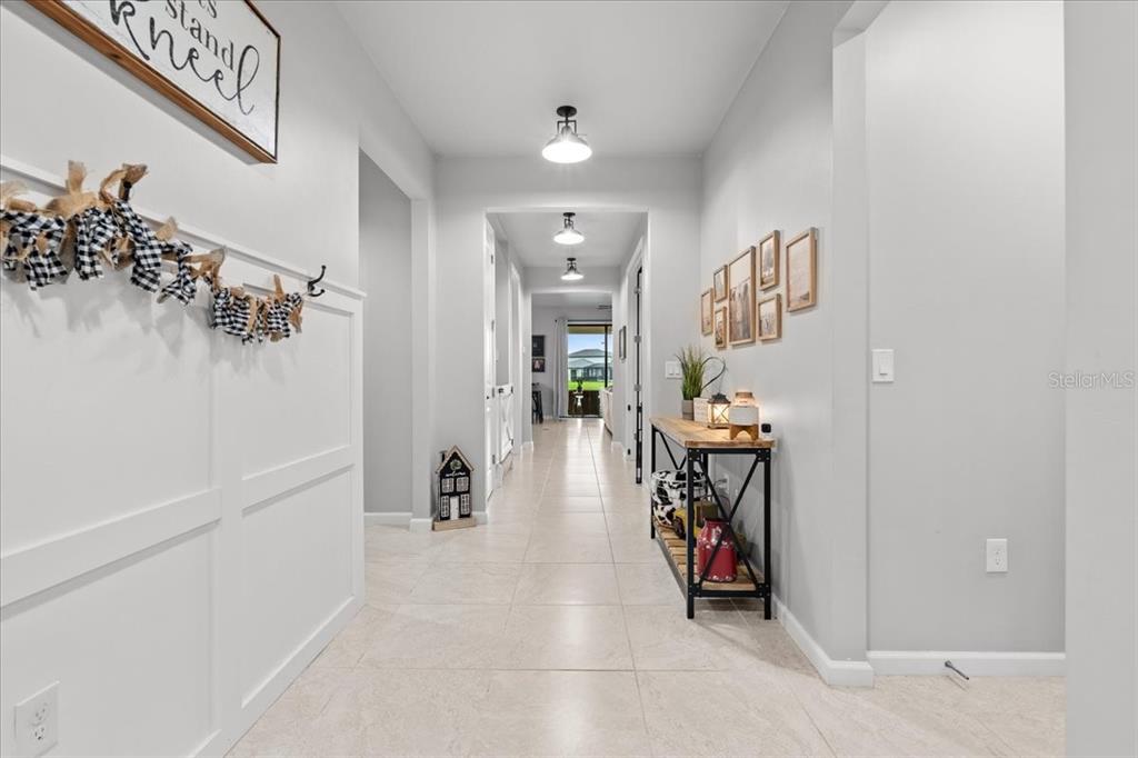 A long, tiled hallway features white board-and-batten walls, a console table, and overhead lighting — 2596 BUCKTHORN LOOP, NORTH PORT, FL