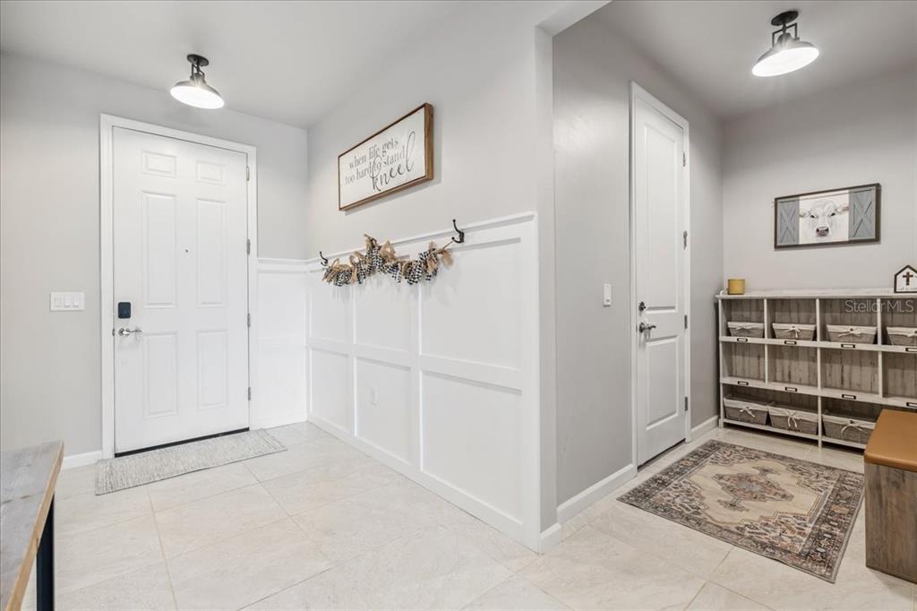 An entryway features white wainscoting, tile flooring, a storage cubby unit, and two overhead lights — 2596 BUCKTHORN LOOP, NORTH PORT, FL