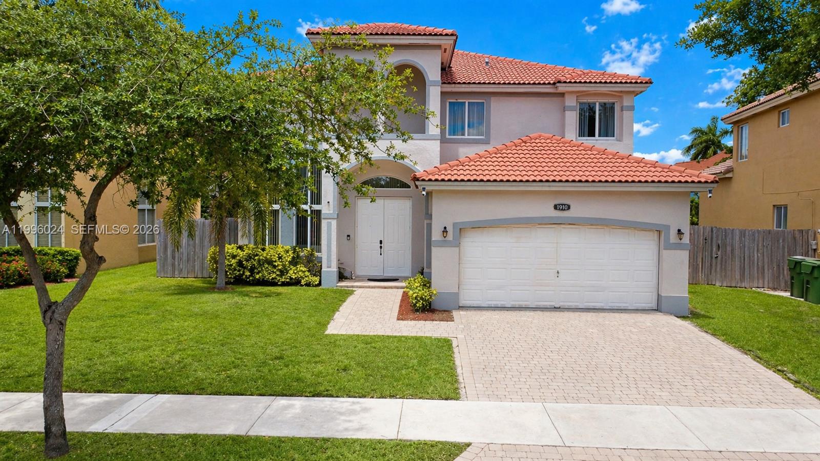 A two-story house with a tiled roof, a two-car garage, and a paved driveway — 1910 SE 14th Cir, Homestead FL 33035, HOMESTEAD, FL