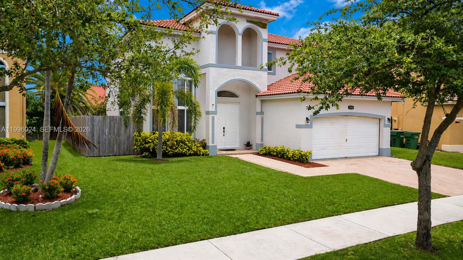 A bright living room features high ceilings, light-colored tile floors, and a multi-panel tree artwork — 1910 SE 14th Cir, Homestead FL 33035, HOMESTEAD, FL