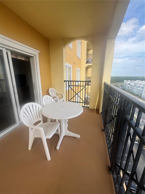 A balcony features a white round table and two chairs overlooking a parking lot — 8101 RESORT VILLAGE DRIVE UNIT 3909, ORLANDO, FL