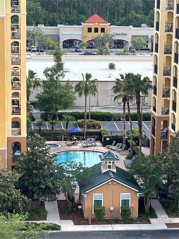 An elevated view shows a swimming pool, a small clubhouse, and nearby retail stores — 8101 RESORT VILLAGE DRIVE UNIT 3909, ORLANDO, FL